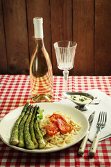 Roasted asparagus and tasty pasta with vegetables on plate on wooden table background