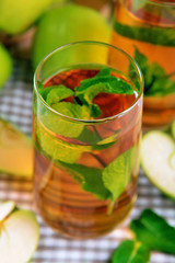 Fototapeta na wymiar Glasses of apple juice with fruits and fresh mint on table close up