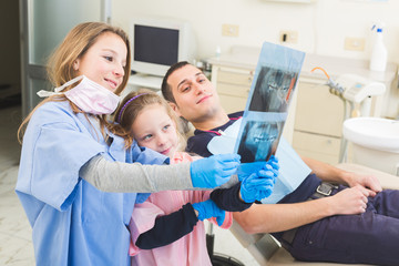 Little dentists looking at x-ray of adult patient