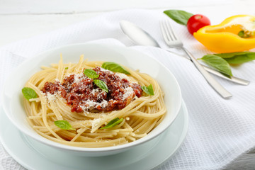 Spaghetti Bolognese with parmesan cheese in white bowl, on color wooden background