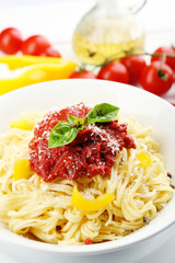 Spaghetti with tomato sauce and cheese on white plate, on color wooden background