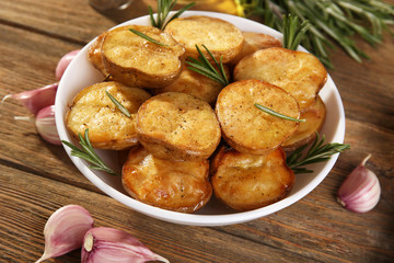 Delicious baked potato with rosemary in bowl on table close up