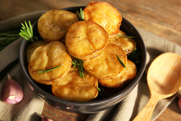 Delicious baked potato with rosemary in bowl on table close up