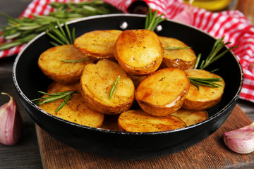 Delicious baked potato with rosemary in frying pan on table close up