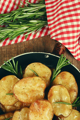 Delicious baked potato with rosemary in frying pan on table close up