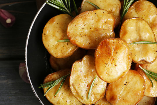 Delicious baked potato with rosemary in frying pan close up