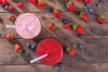 Glasses of berry smoothie on wooden table, top view