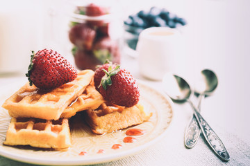 Sweet homemade waffles with forest berries and sauce on table background