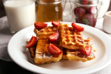 Sweet homemade waffles with strawberries  on plate, on table background