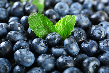 Tasty ripe blueberries with green leaves close up