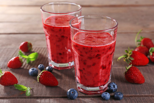 Glasses of berry smoothie on wooden table, closeup