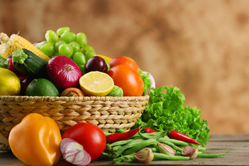 Heap of fresh fruits and vegetables in basket on wooden table close up