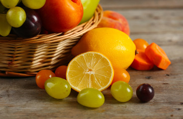 Heap of fresh fruits and vegetables in basket on wooden table close up