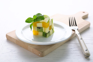 Fruit salad on plate, on light wooden background