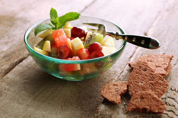 Fruit salad in glass bowl, on  wooden background