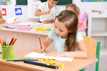 Little girl drawing at the desk in classroom