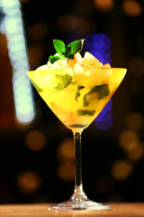 Glass of cocktail on dark blurred lights background