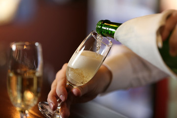 Bartender pouring champagne into glass, close-up
