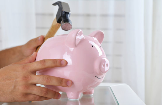 Hand with a hammer going to break the piggy bank, close up