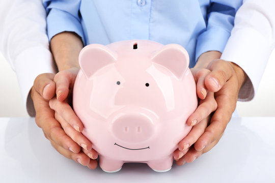 Man and woman hands holding piggy bank