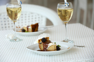 Delicious cake under chocolate glaze with blackberry and wine glass on the table
