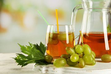 Grape, glass and jug with juice on white table