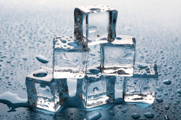 Melting ice cubes putted as pyramid with drops around, close up