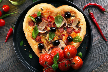 Heart shaped pizza on metal tray on wooden table