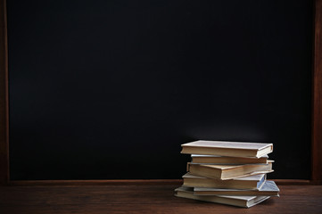 Books on the table on blackboard background