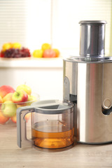 Juicer and apple juice on kitchen table