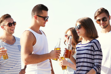 Young people with beer on the riverside