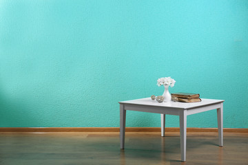 Little table with flowers and books on blue wall background