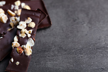 Black chocolate pieces and nuts on dark gray background