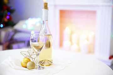 Bottle and glass of wine with Christmas decor against colorful bokeh lights background