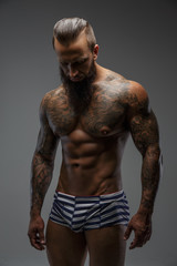 Fototapeta na wymiar Muscular nude man with tattooed body.