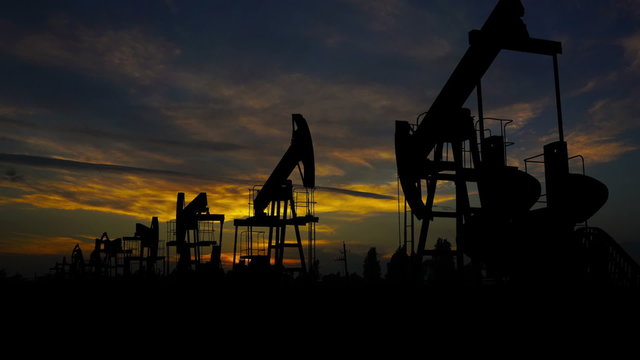 working oil pumps silhouette against timelapse sunset
