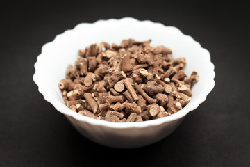 Organic Ganthoda or Long pepper Roots (Piper longum) in white ceramic bowl on dark background.