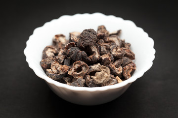 Organic Dried gooseberry or Amla (Ribes grossularia) in white ceramic bowl on dark background.