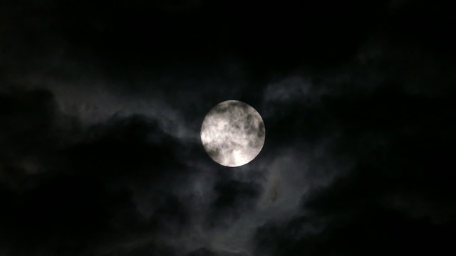 full moon moving between clouds
