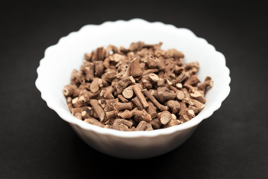 Organic Ganthoda or Long pepper Roots (Piper longum) in white ceramic bowl on dark background.