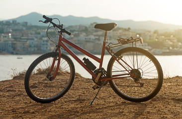 Red bicycle on the hill at sunset.