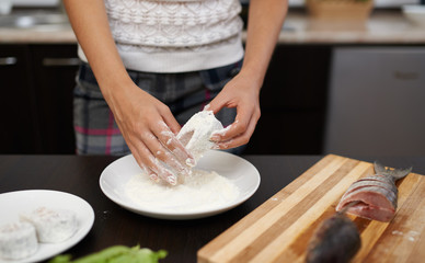 Obraz na płótnie Canvas girl roll slice of fish in flour