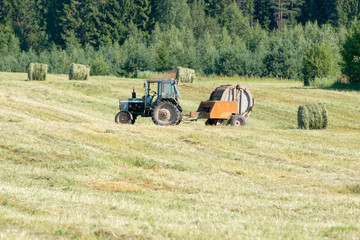 Fototapeta na wymiar Tractors mow grass and packed