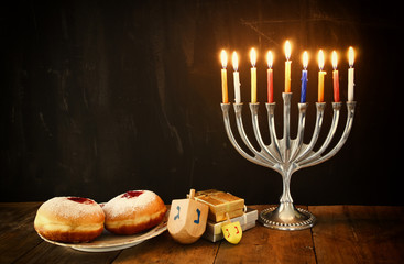 image of jewish holiday Hanukkah with menorah (traditional Candelabra), donuts and wooden dreidels (spinning top).