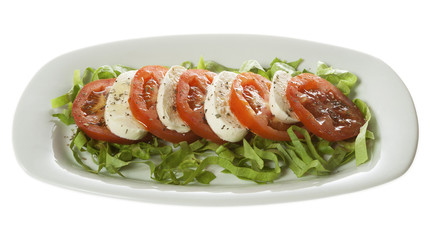 Italian salad - Caprese salad, tomato and mozzarella with spices, served on a white plate. Isolated on white.