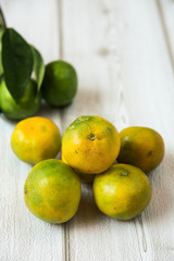 Ripe sweet lemon and tangerine with leaves on wooden board