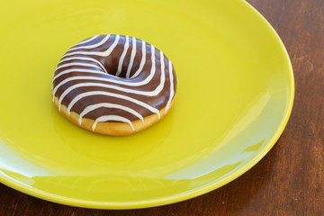 donut with chocolate zebra colors on the color plate and brown background. top view. space for inscriptions.