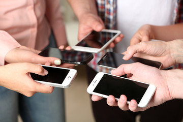Many hands holding mobile phones close up