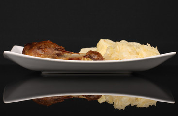 Roast duck, cabbage and dumplings on black background