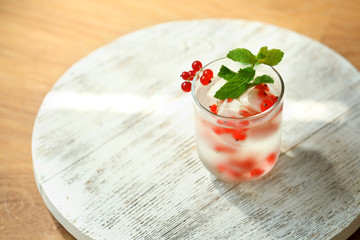 Glass of cold refreshing summer drink with berries and ice cubes on table close up
